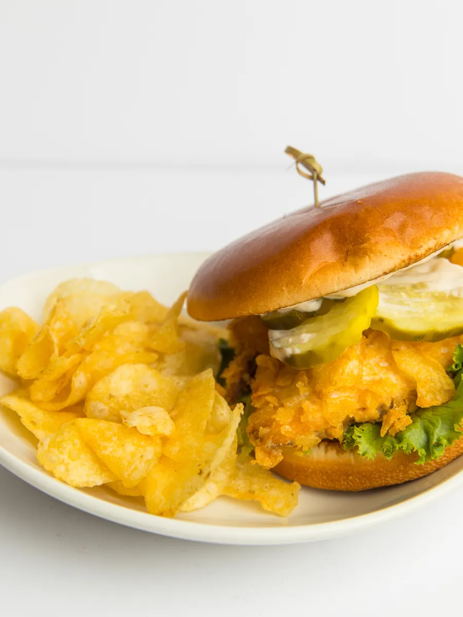 fish sandwich with pickles and a side of chips
