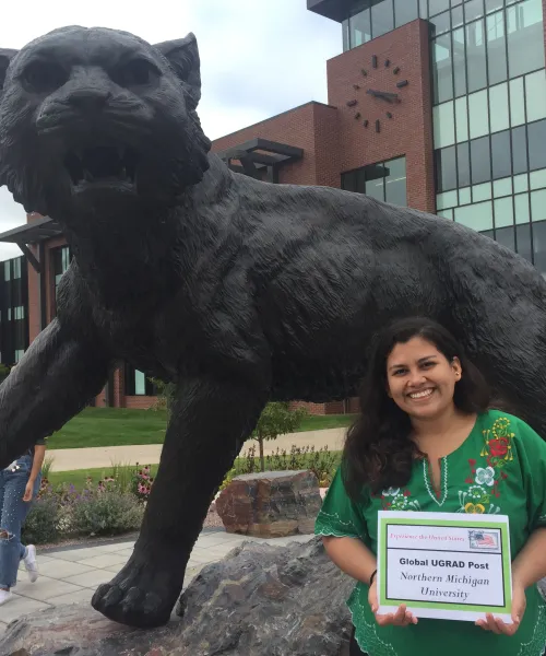 Student next to statue of wildcat 