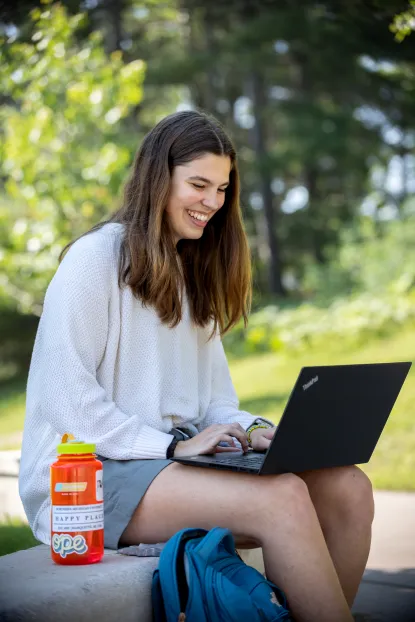 Girl typing on laptop outside